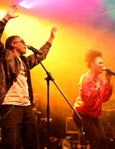 Jammin’Cool Rapper Soul Elements performt mit einer Sängerin vor orange-gelbem Bühnenlicht